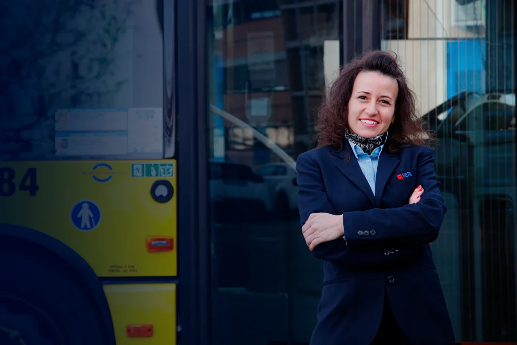 Autista di autobus sorridente con divisa davanti a un autobus SETA.