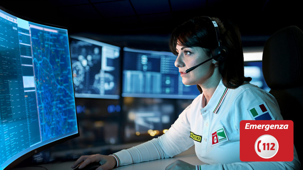 Operatrice 112 al lavoro con cuffie e schermi