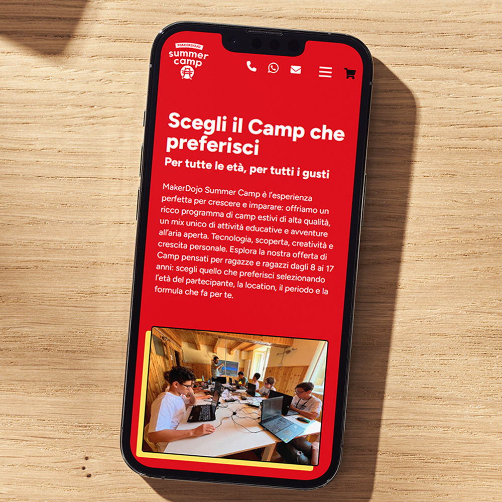 Smartphone su scrivania in legno con pagina Shop del sito web di MakerDojo
