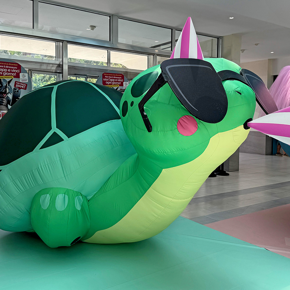 Una grande tartaruga gonfiabile con occhiali da sole e cappello da festa è esposta al centro commerciale Fiumara.